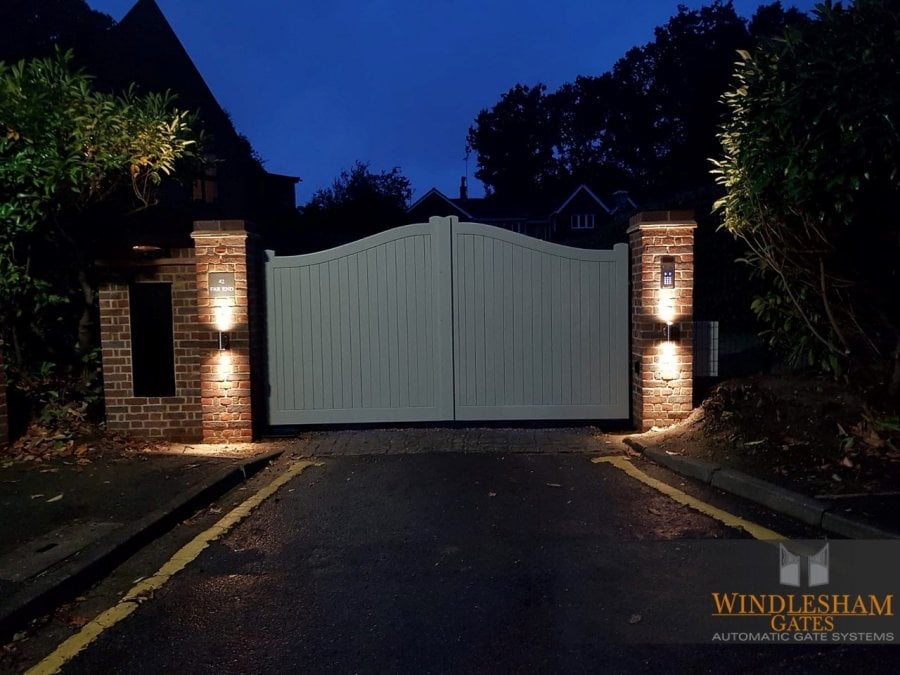 Electric gate at night with brick columns with lights attached
